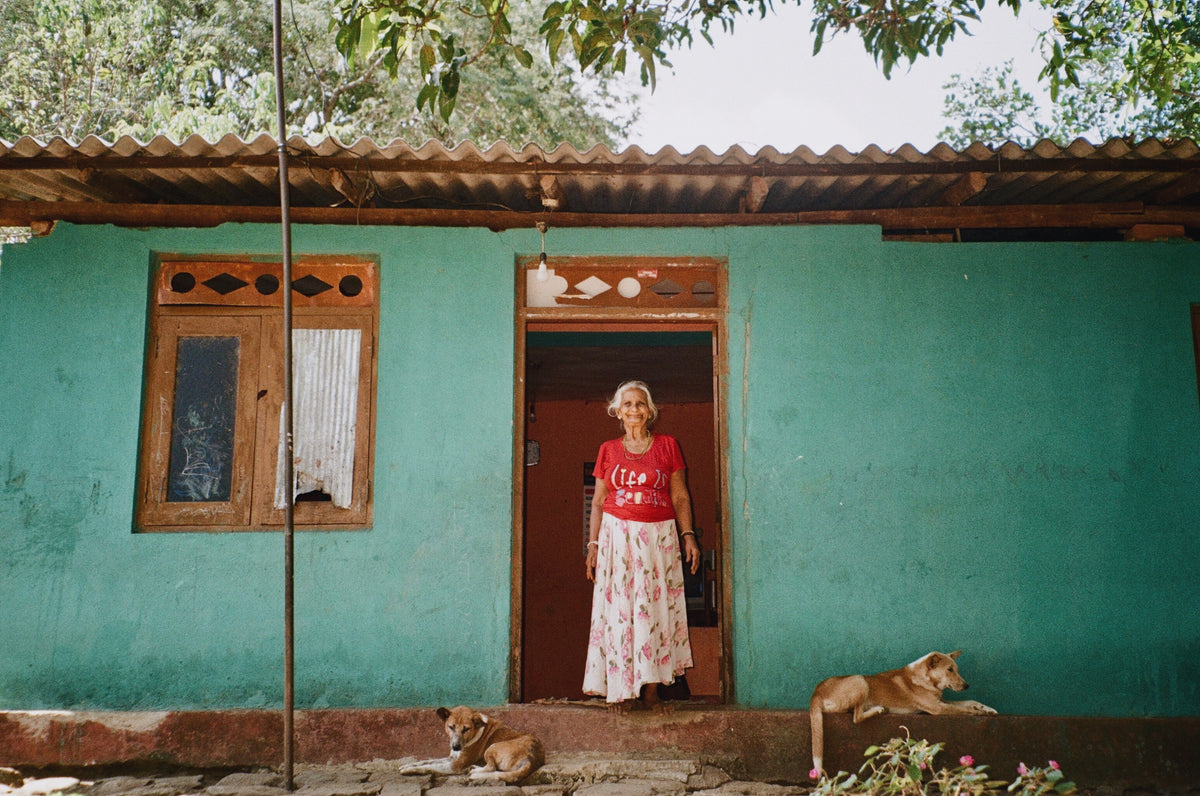 Weathered turquoise cottage with an elderly woman and dogs