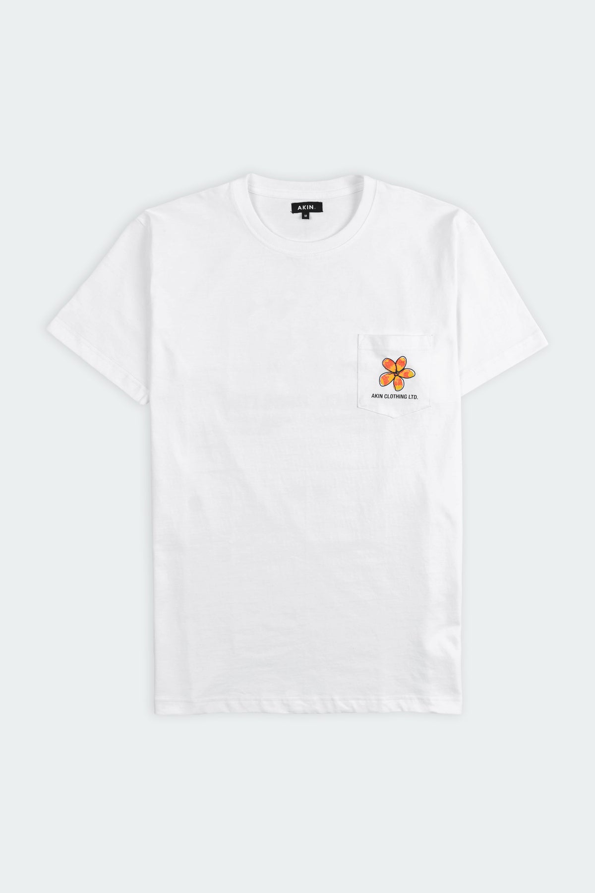 Ceylon Bloom white pocket t-shirt flat lay, small orange flower graphic and Akin Clothing Ltd text on chest
