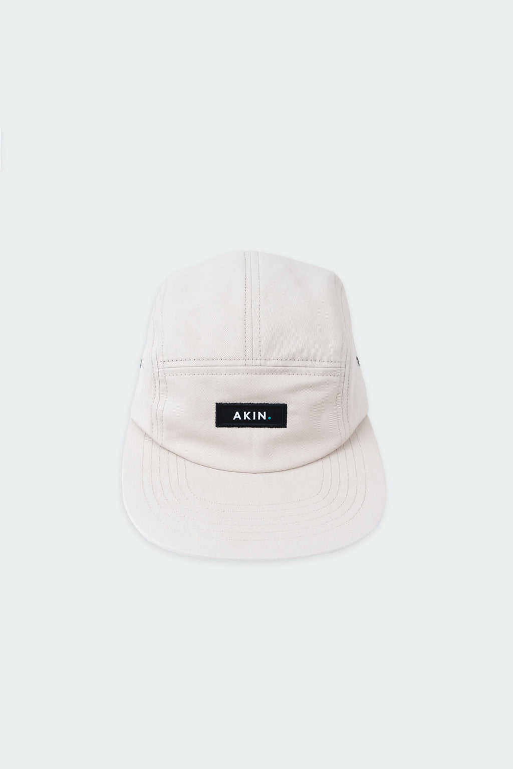 Beige Akin Five Panel Cap, front view with black AKIN label, product flat lay