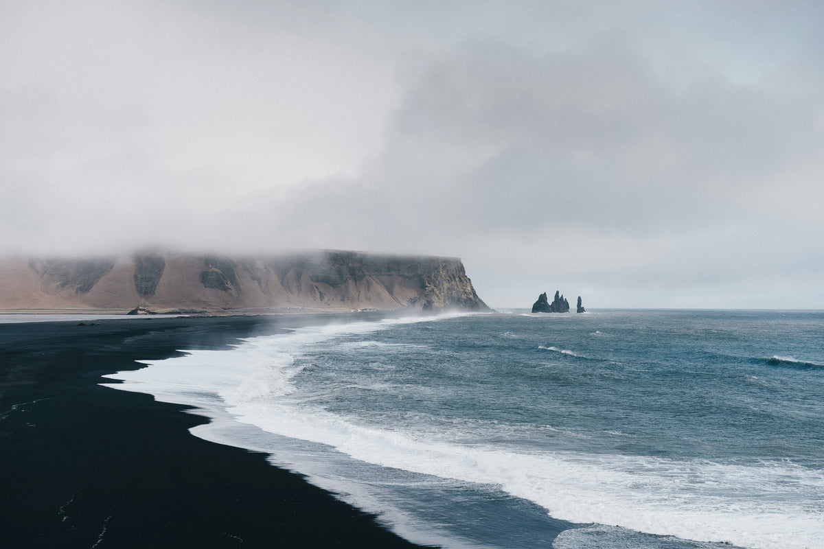 A surfer riding a long wave beneath an open horizon